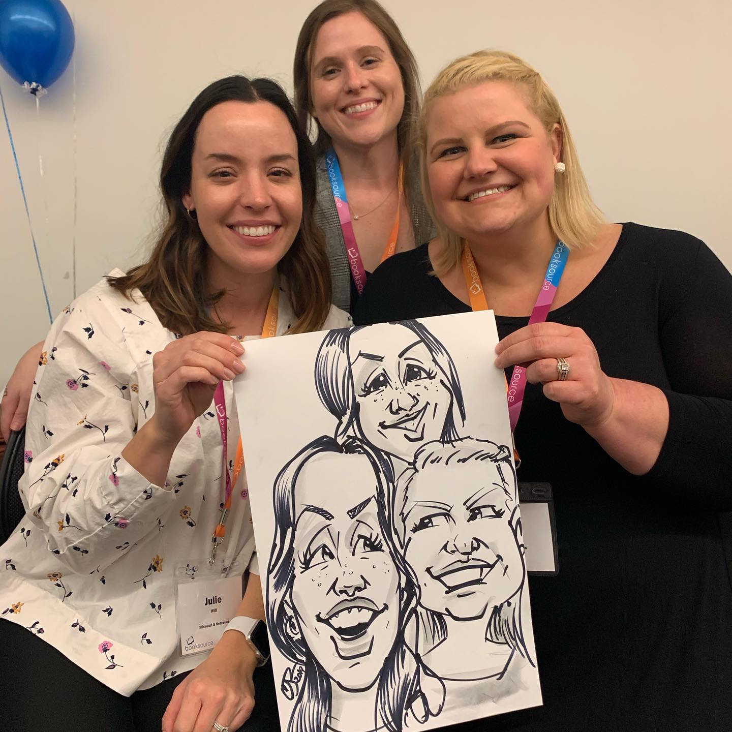Three women smile as they hold their new caricature