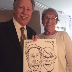 A happy couple holds their caricature at a wedding reception. A smiling couple holding their caricature